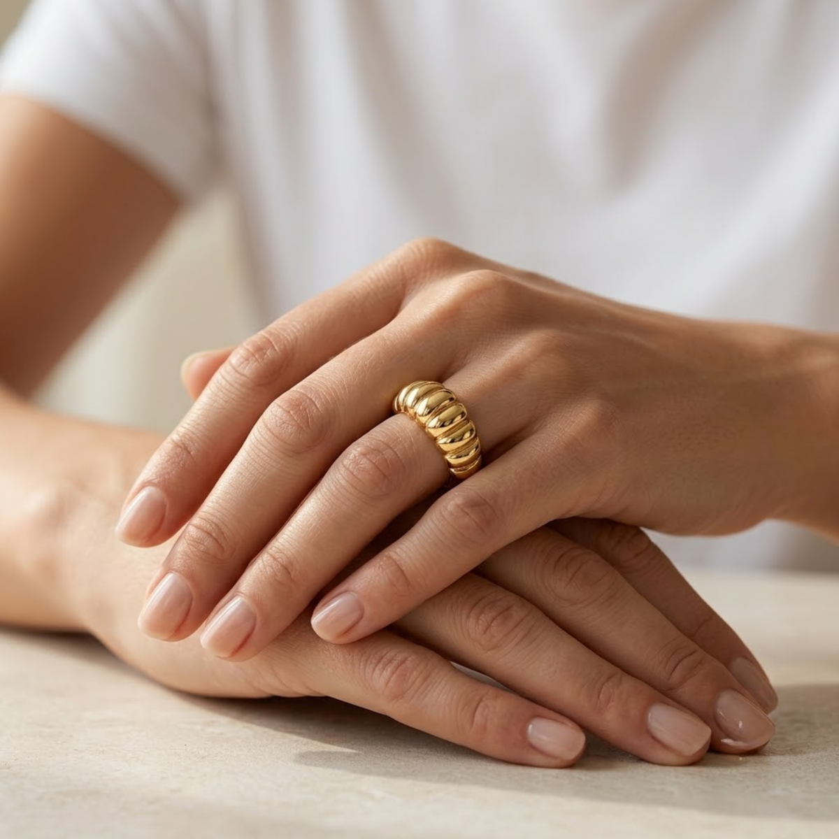 Anillo croissant de oro amarillo 14k puesto en la mano sobre fondo neutro