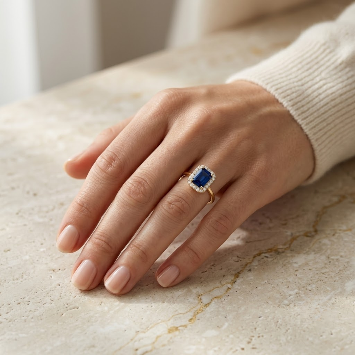 Anillo de zafiro rectangular con halo de diamantes puesto en la mano